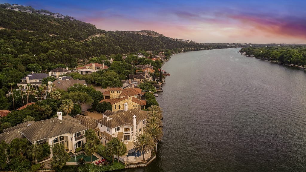 Lake Austin at dusk, hillside homes and boat docks along the north shore